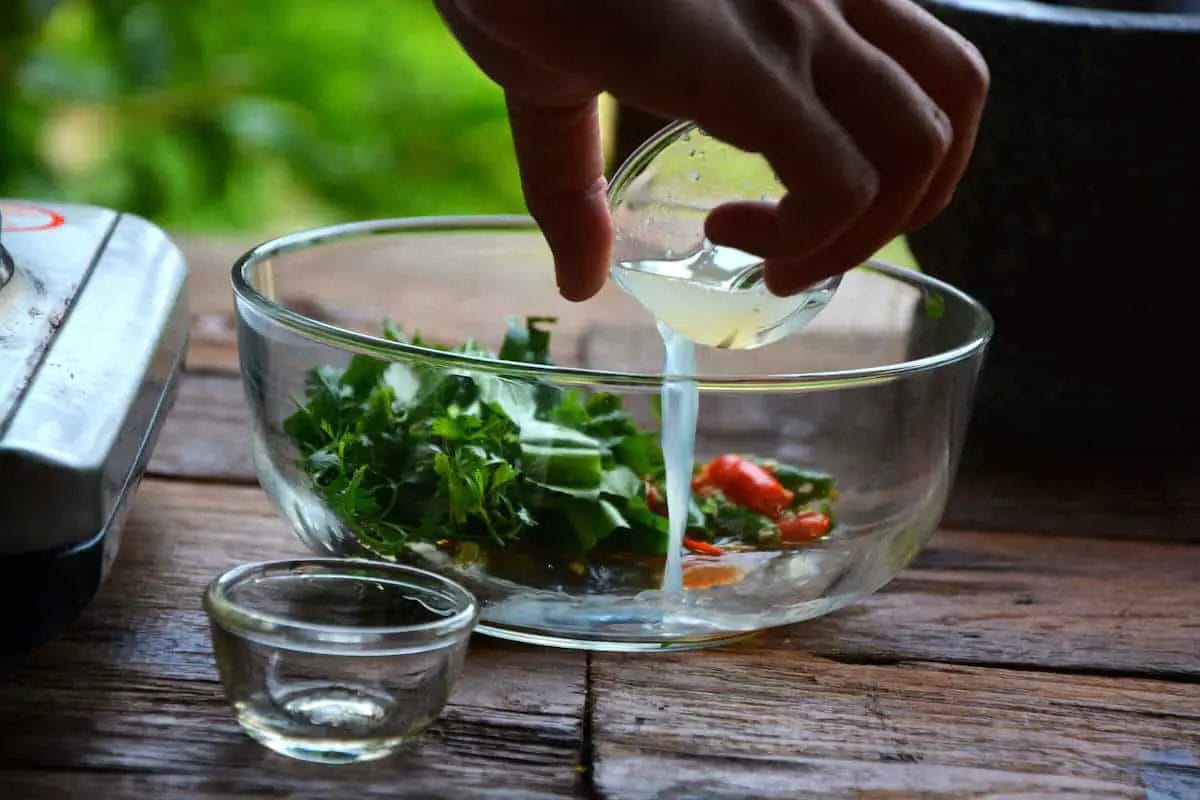 pouring fresh squeezed lime into bowl for tom yum recipe prep