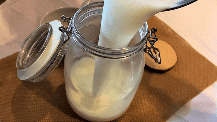 pouring milk for yogurt in glass jar